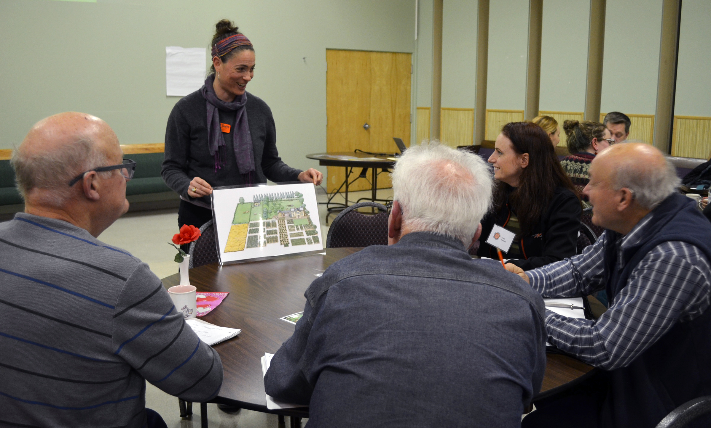 Woman leads discussion about a garden map with a group of community members at an educational event